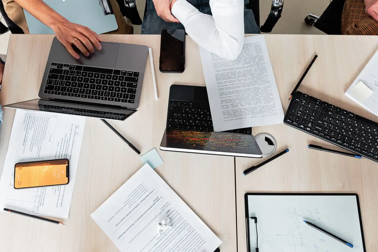 Laptops, papers and notebooks arranged on a work table.